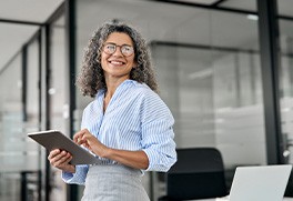 a smiling businesswoman with glasses holding a tablet