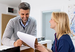 a person in scrubs handing a patient forms