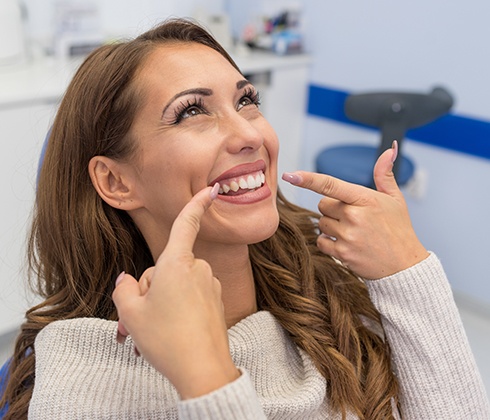 Woman pointing to smile after fully personalized dental care