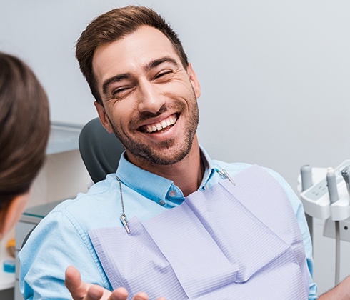 Man in dental chair laughing during dentistry visit