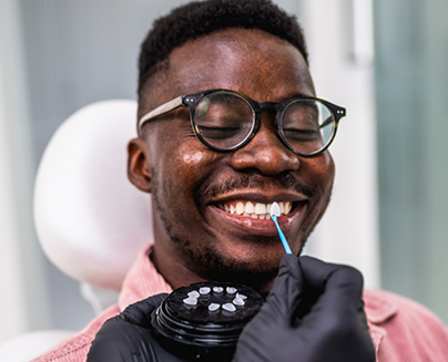 Man with glasses having teeth shade matched for veneers