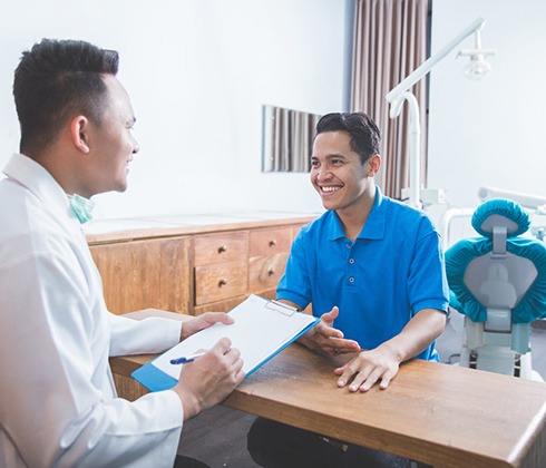 patient smiling while dentist explains dentures 