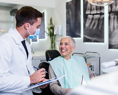 Dentist with mask talking to senior dental patient