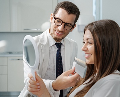 a dentist holding a shade chart in front of a smiling patient