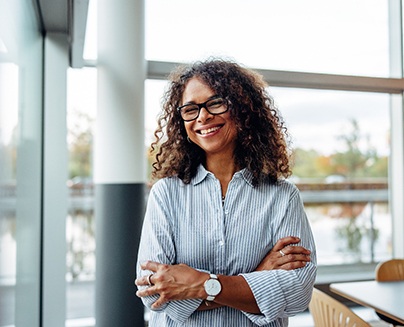 a smiling woman standing with her arms crossed
