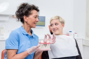 a dentist in Midlothian explains how dental implants work for a female patient