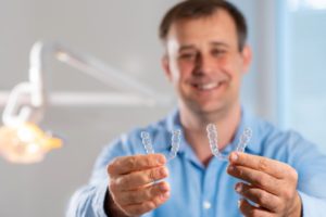 middle-aged man holding Invisalign aligners