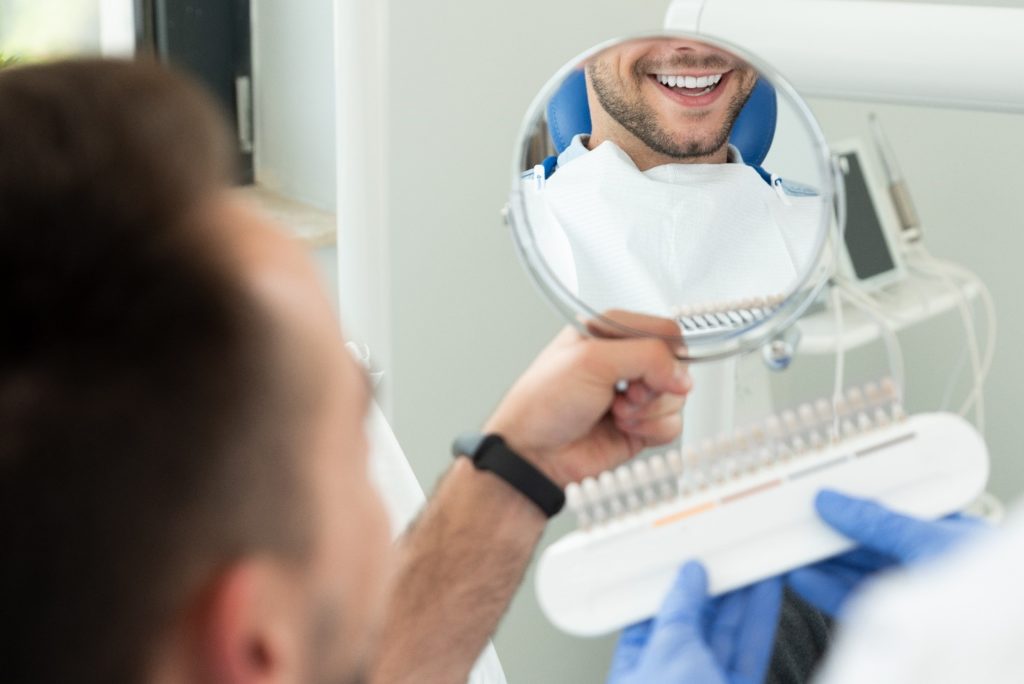 Patient with dental implants smiling in reflection