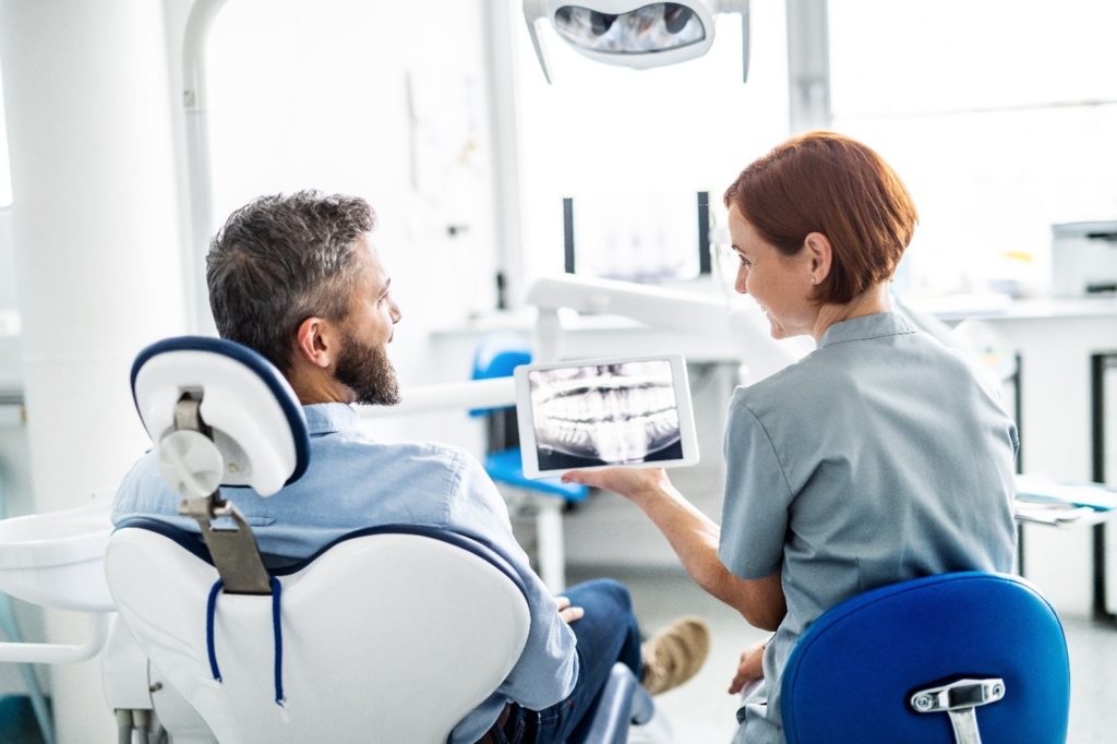 Smiling dentist showing patient X-ray