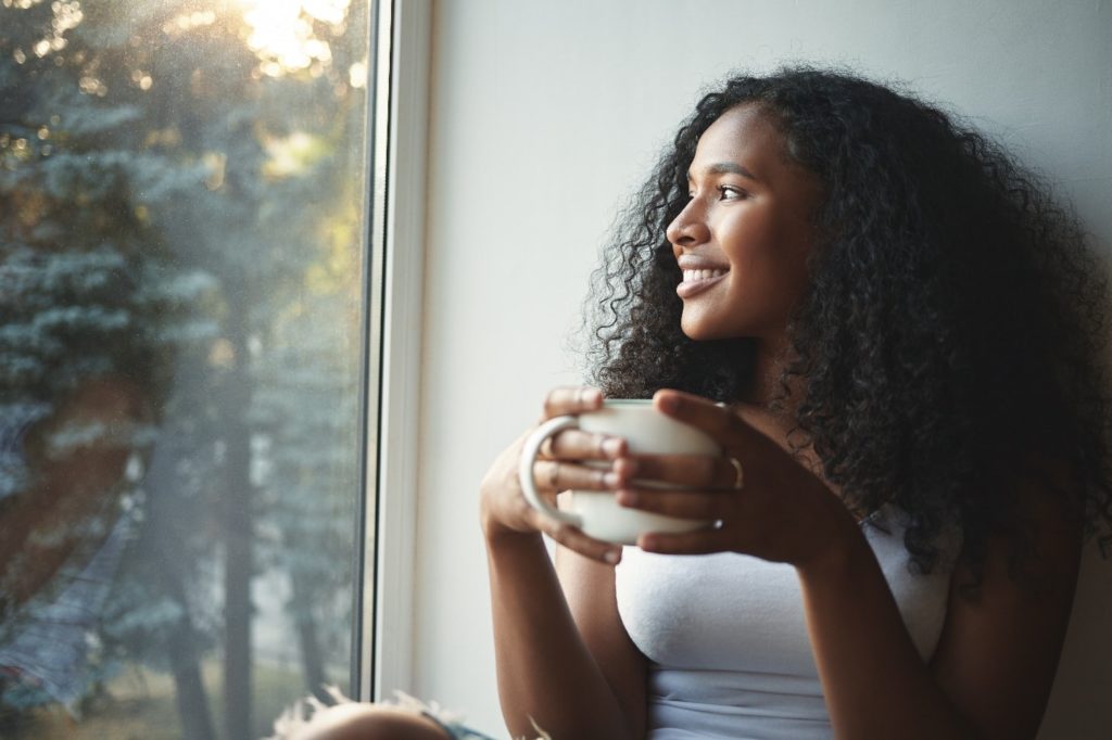 Woman smiling while drinking cup of green tea