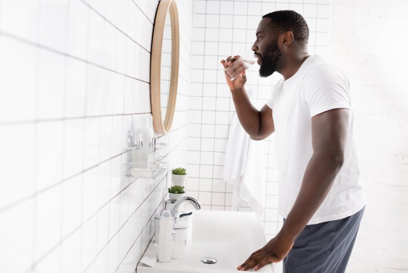 man rinsing mouth in bathroom
