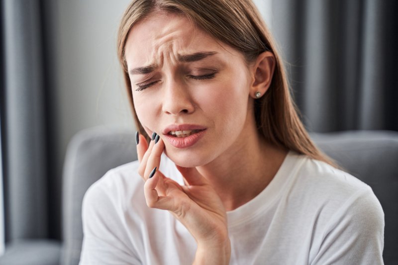 young woman touching painful jaw with hand