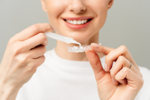 a woman putting whitening gel in a dental tray